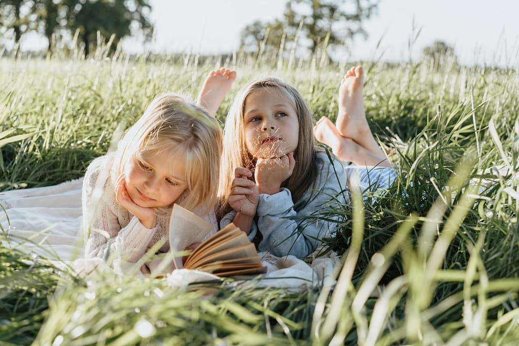 two girls lying in tall grass on a spring day