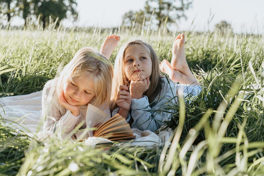 two girls lying in tall grass on a spring day